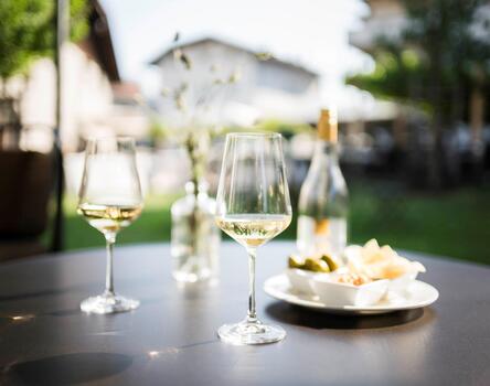Due calici di vino bianco e alcuni stuzzicchini su un tavolo in giardino