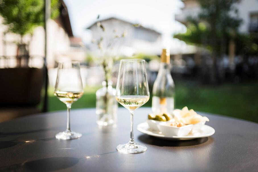 Due calici di vino bianco e alcuni stuzzicchini su un tavolo in giardino