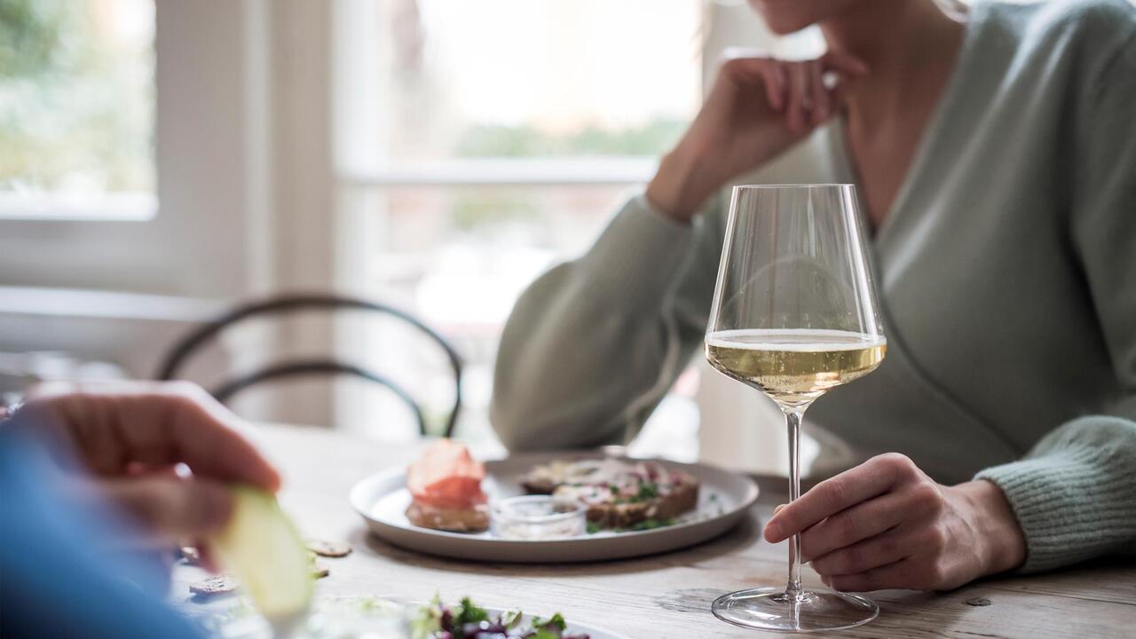 A woman with a glass of white wine during a meal
