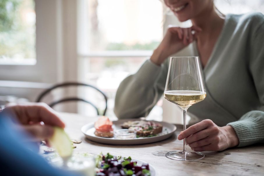 Eine Frau mit einem Glas Weißwein beim Essen