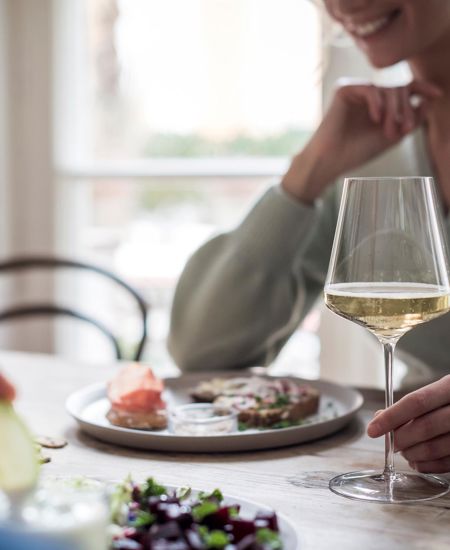 Una donna con un calice di vino bianco durante un pasto