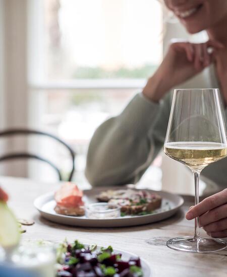 Una donna con un calice di vino bianco durante un pasto